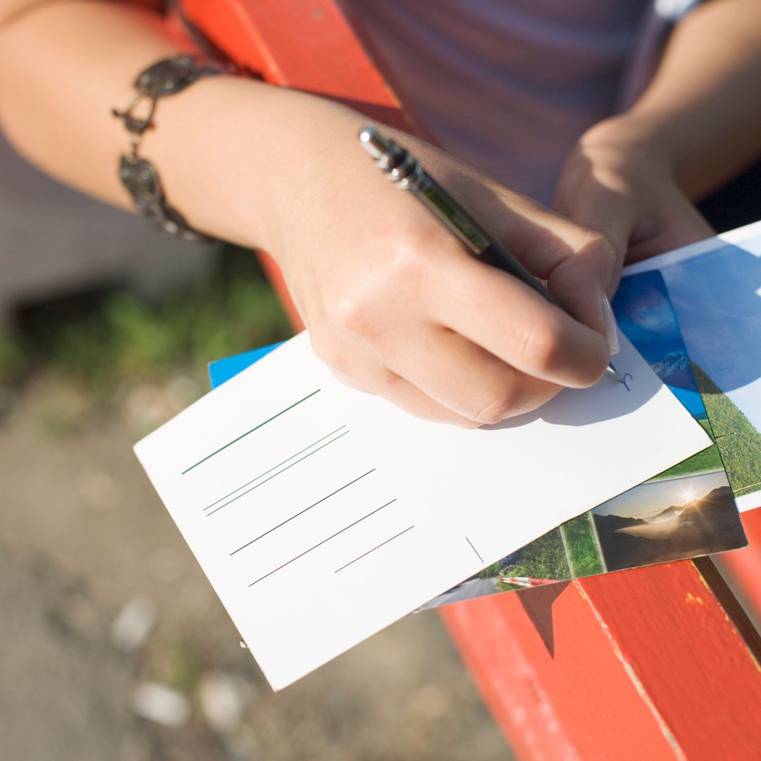 Person writing on postcard