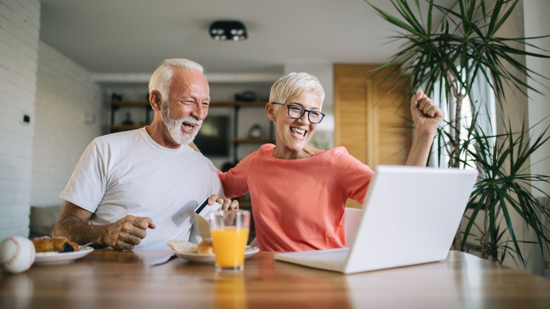 Couple celebrating in front of laptop after winning online auction