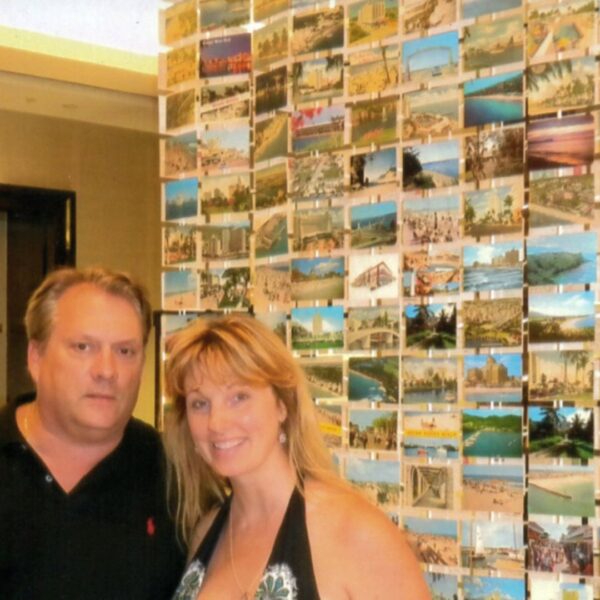 Owners of Mary L. Martin Vintage Postcards standing in front of postcard wall