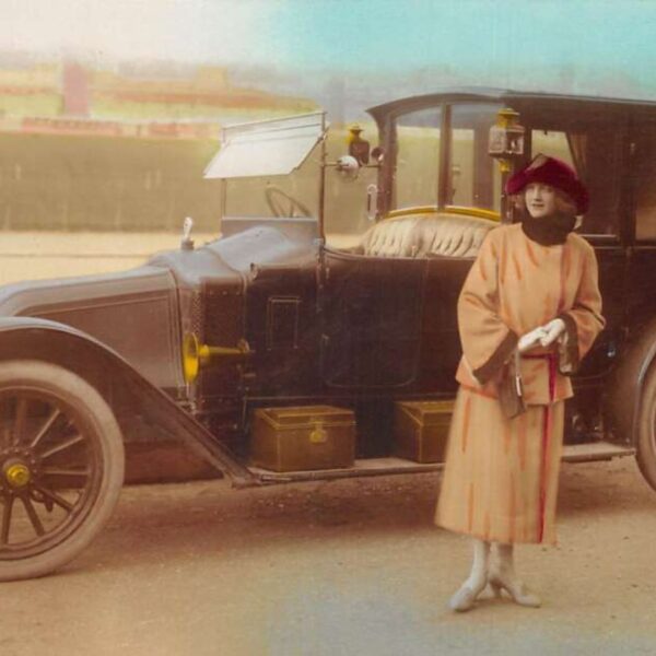 Vintage postcard of woman infront of a car